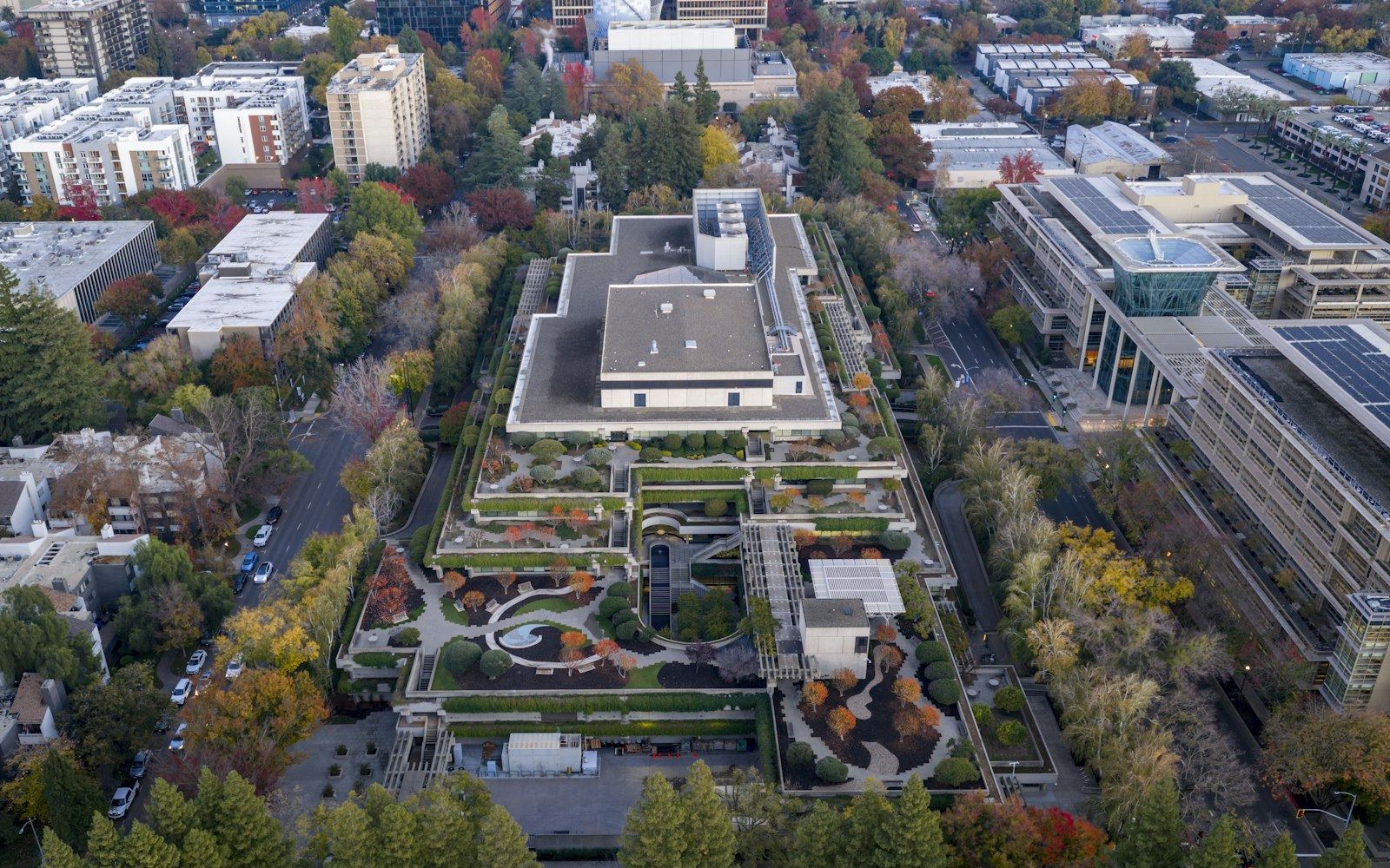 Vista aérea de un campus industrial moderno con cubiertas verdes rodeado de arboleda