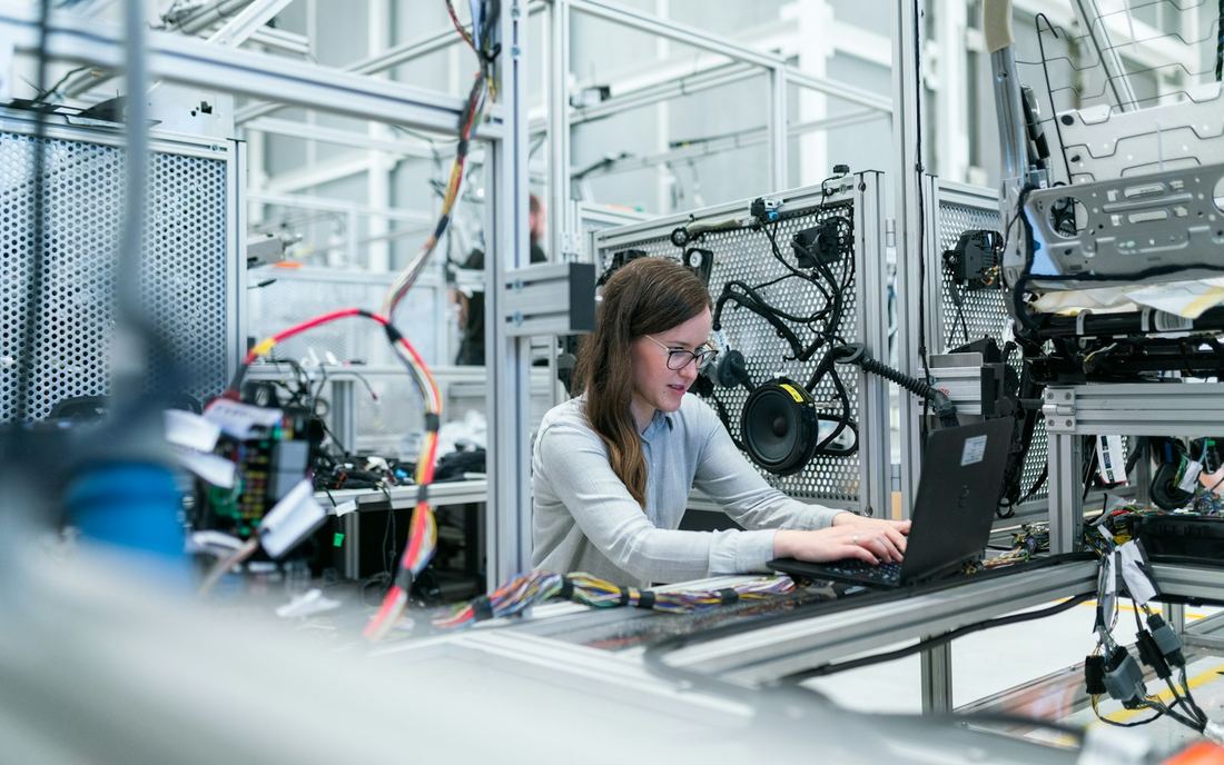 Técnica trabajando frente a un panel en una planta industrial